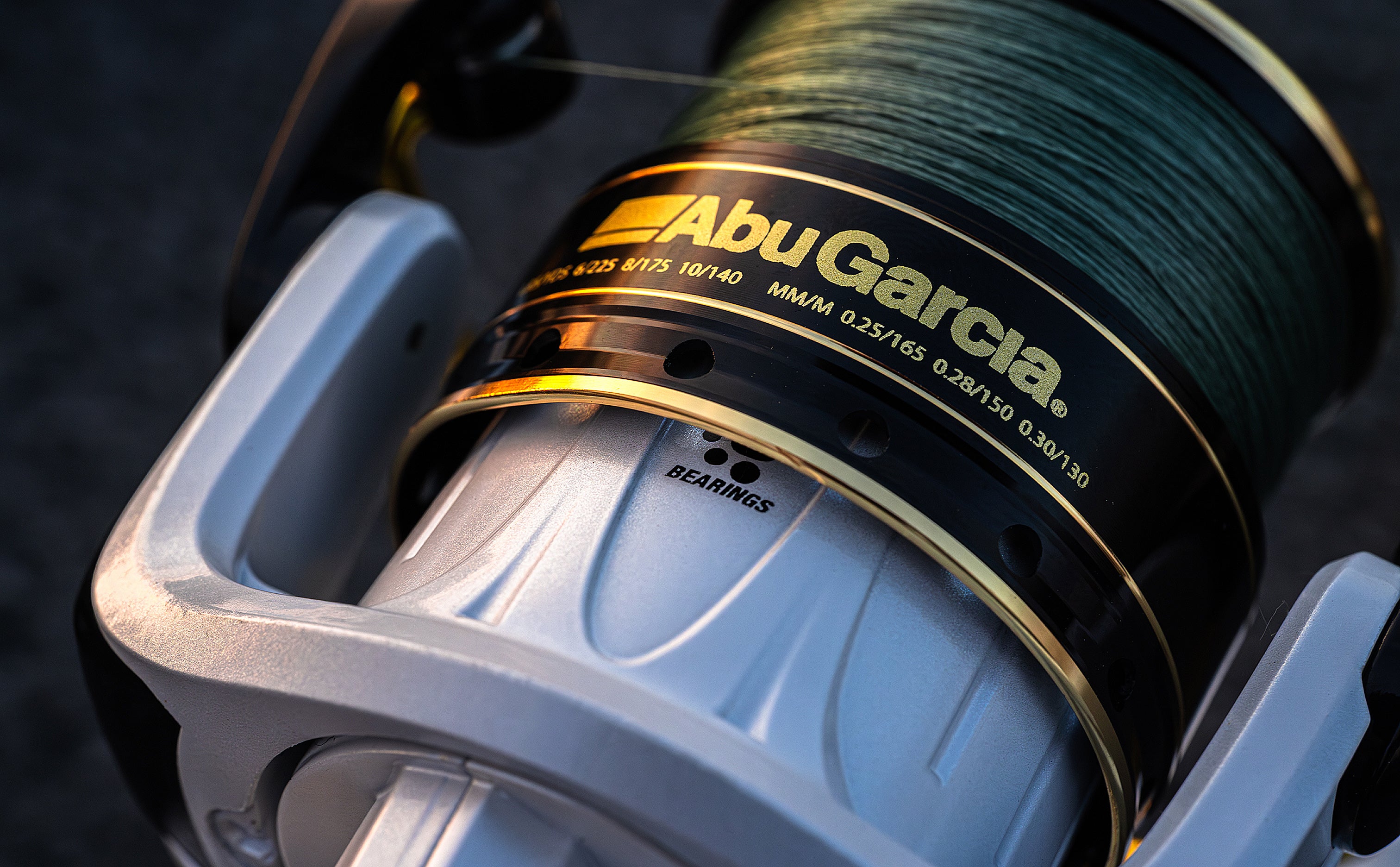 Close-up of Abu Garcia fishing reel with green line on a dark background