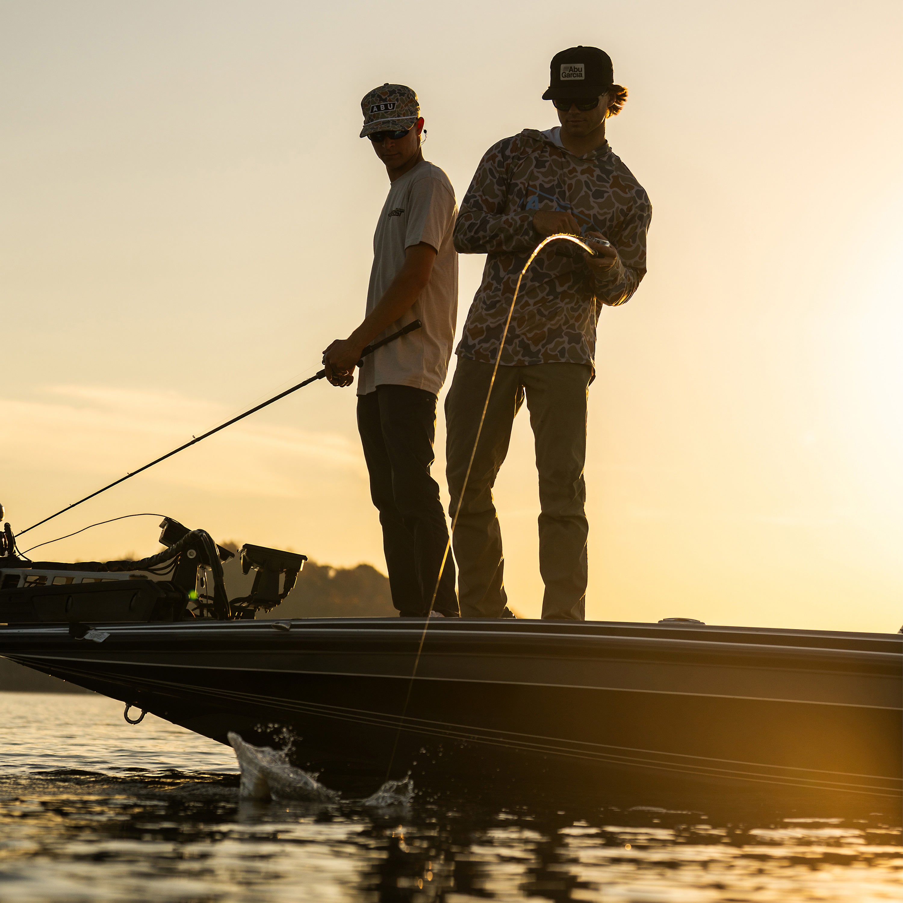Two people on a boat at sunset, engaged in fishing.