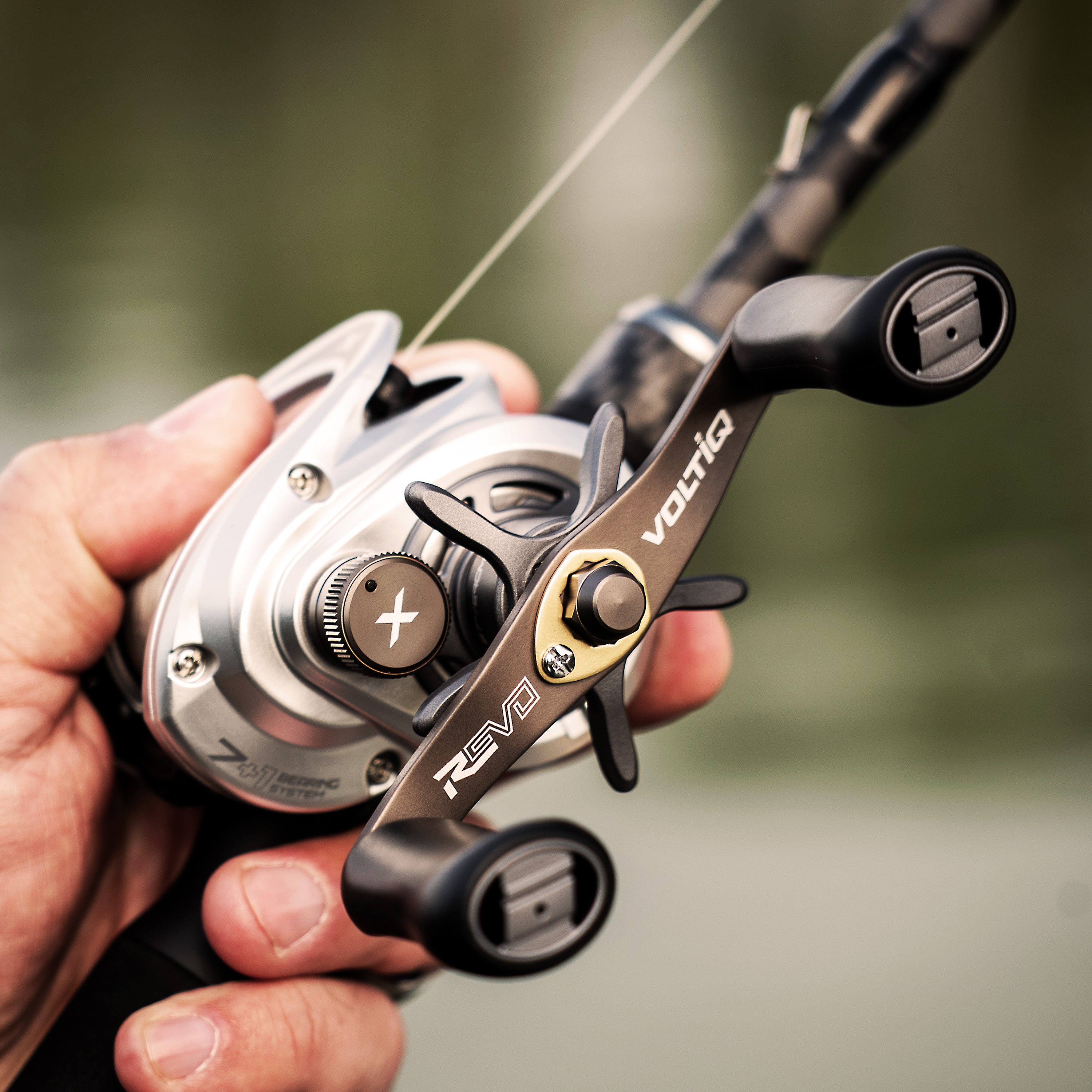 Fishing reel held in a hand with a blurred background
