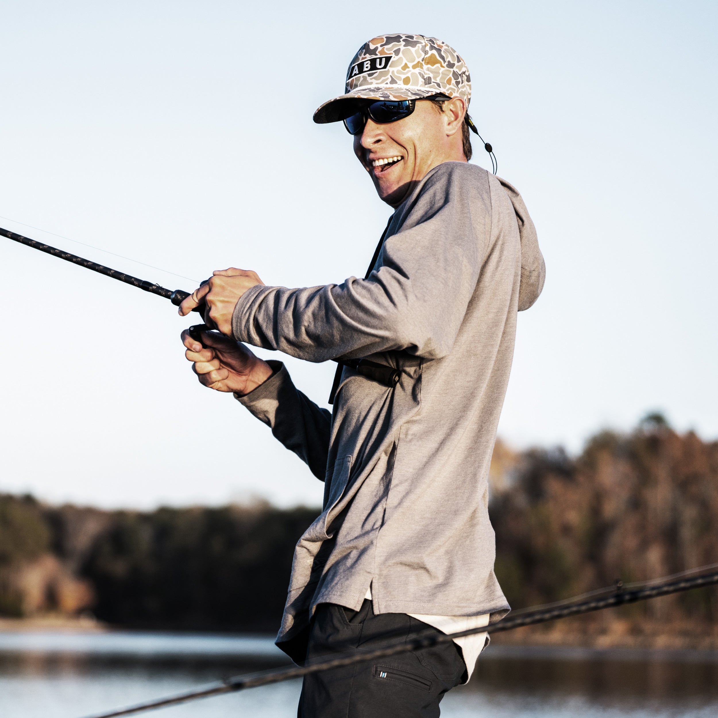 Man fishing by a lake with trees in the background