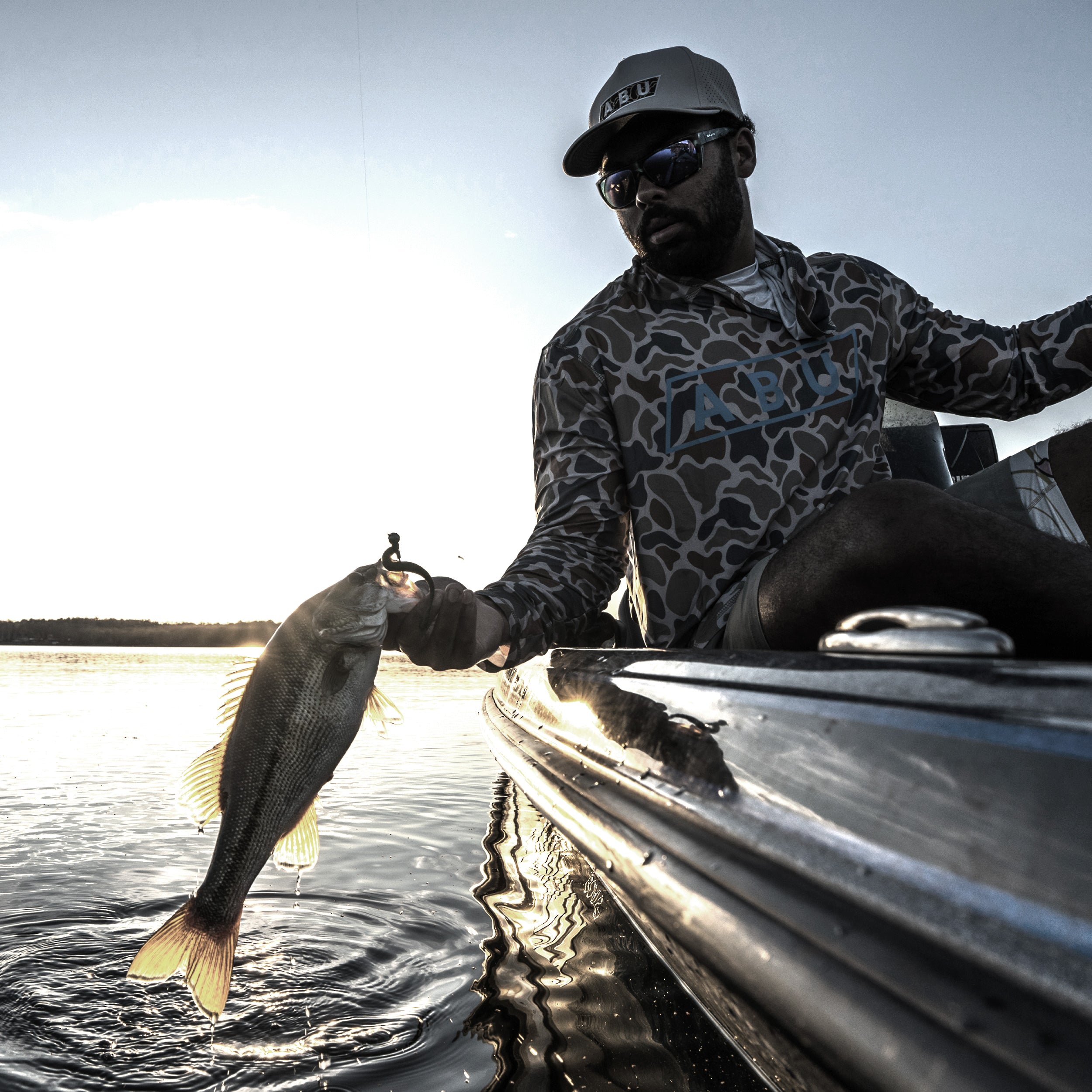 Man holding a fish on a boat with a lake background